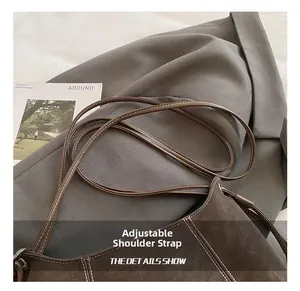 Detail of adjustable shoulder strap and contrast stitching on dark brown shoulder bag