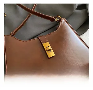 Detailed macro view of the vintage brown leather bag featuring a gold rectangular clasp