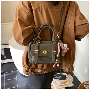 Detail view of vintage olive green mini square bag with golden lock and plush animal charm
