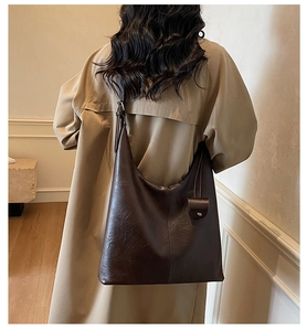 Detail of a large vintage brown tote bag with leather texture and small round pendant
