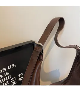 Detailed close-up of adjustable long shoulder strap and zipper on brown tote bag
