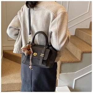 Detail of vintage square bag with gold twist lock and cute bear charm in use