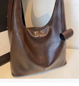 Detail of soft dark brown leather texture and vertical stitching on the tote bag