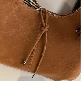 Detail of brown faux suede tote bag featuring silver zipper and striped fabric lining