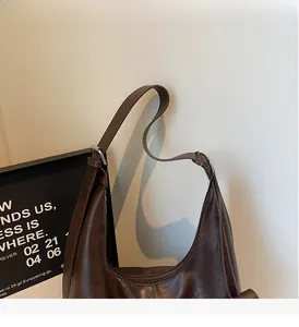 Detail of dark brown leather texture and adjustable wide shoulder strap of the hobo bag