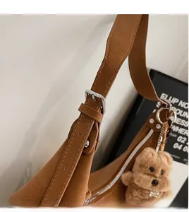 Close-up of adjustable shoulder strap with silver buckle and brown plush bear charm
