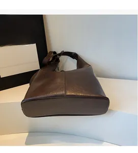 Close-up of dark brown vintage leather tote bag showing smooth texture and wide strap