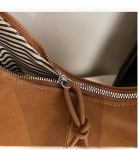 Detail of smooth silver zipper with brown matte cord pull and striped fabric lining