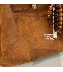 Close-up of brown suede tote bag with metal buckle and bohemian wooden bead charms