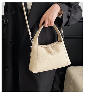Close-up of beige lychee texture leather shoulder bag with metallic buckle detail