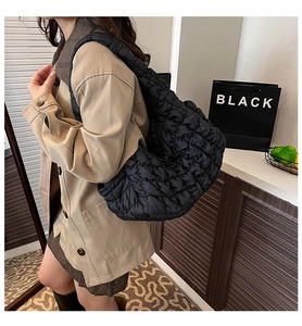 Détail d'un grand sac cabas noir matelassé porté par un mannequin montrant le nylon doux