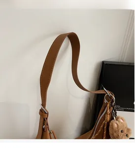 Detail of caramel faux leather shoulder bag strap with silver zipper and bear charm