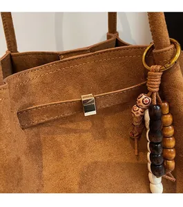 Close-up of brown suede tote bag featuring silver buckle and retro beaded wooden charm