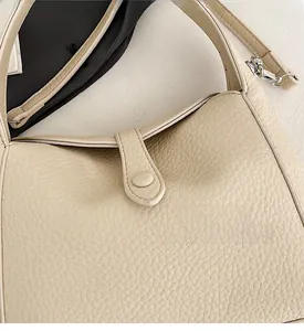 Detailed macro of cream lychee-grain leather texture and silver hardware on a shoulder bag