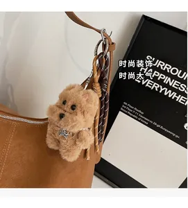 Detail of brown leather shoulder bag with a plush dog charm and fine decorative stitching