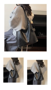 Detail shot of black leather tote bag showing smooth texture and strap attachment