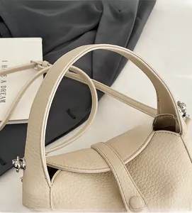 Macro detail of beige pebble grain leather texture and metal hook on shoulder bag