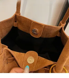 Detail of magnetic buckle closure on large brown matte faux suede tote bag
