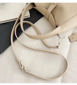 Detail of adjustable beige lychee leather strap with silver metal buckle on shoulder bag