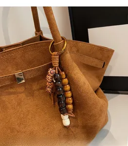 Detail of bohemian beaded charm with wooden accents on a brown suede shoulder bag