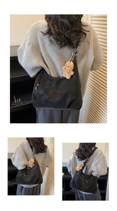Macro detail of a large black Hobo shoulder bag with a cute brown teddy dog pendant charm