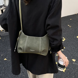 Detail of dark green leather shoulder bag with fine stitching and gold logo lettering