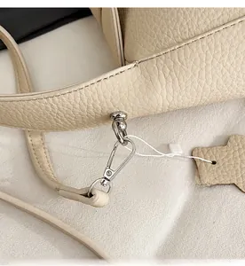 Detail view of silver metal hook and pebble grain leather on cream underarm bag