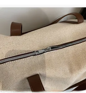 Nahaufnahme vom glatten Metallreißverschluss und braunem Lederbesatz der Segeltuchtasche