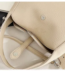 Detail view of the secure magnetic clasp on this beige textured leather shoulder bag