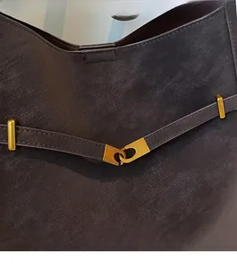 Close-up of golden alloy hook buckle and premium natural leather texture on bucket bag