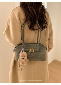 Detail of olive green suede underarm bag with metal buckle and plush bear charm