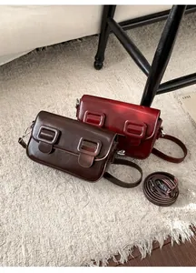 Detail van glanzende lederen crossbodytassen in donkerbruin en wijnrood op beige imitatiebont