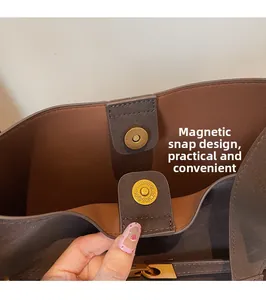 Detail of the dual magnetic snap closure on a brown leather tote with fine engraving