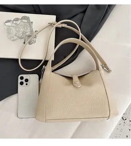 Detailed view of cream-white pebble leather bag with smartphone for size reference