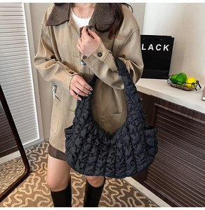 Gros plan du sac hobo matelassé noir à texture bulles porté par un mannequin en intérieur