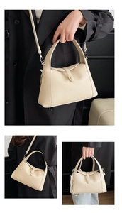 Close-up of beige lychee grain leather handbag with top handle and crossbody strap