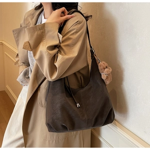 Detail of dark brown faux suede hobo bag with teddy charm on a trench coat model