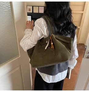 Detail of olive green suede tote bag with wooden bead tassel and soft shoulder straps