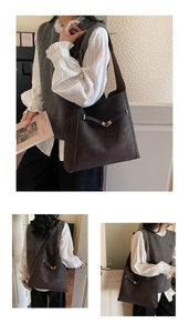 Detail of dark brown leather tote bag with vintage texture and gold arrow metal buckle