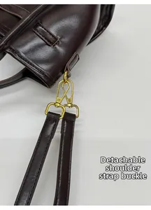 Close-up of dark brown leather bag showing detachable strap and gold metal buckle