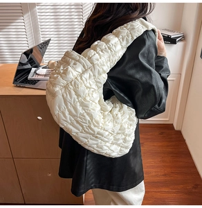 Gros plan d'un sac cabas matelassé blanc porté à l'épaule dans un bureau chic