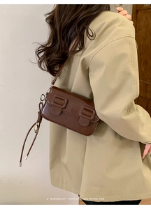 Donkerbruine retro PU-lederen schoudertas met gespen gedragen op beige blazer