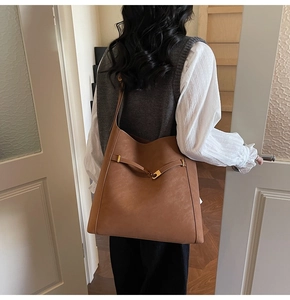 Detail view of a large brown bucket bag showing the metal buckle strap and matte texture