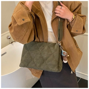 Olive green quilted crossbody bag with plush bear charm and adjustable wide strap detail