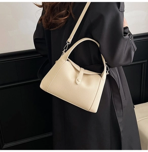 Detail view of lychee grain leather texture and buckle strap on a beige crossbody bag