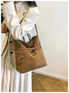Détail d'un cabas marron en daim avec boucle de ceinture et charms en forme d'étoile
