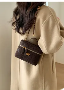 Detail of dark brown quilted crossbody bag with gold chain strap on beige coat