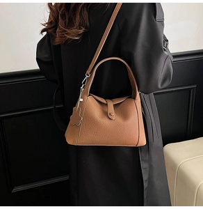 Detail of vintage brown lychee leather bag featuring a floral charm and detachable strap