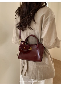 Detail view of burgundy leather shoulder bag with matching mini purse charm and gold buckle
