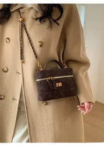 Detail of dark brown quilted suede mini bag with gold hardware and chain strap